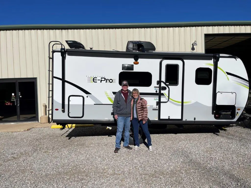 Smiling duo beside their RV