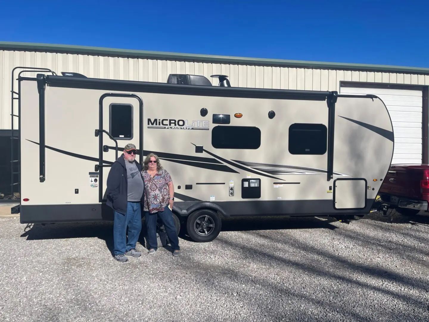 Couple standing beside a travel trailer.
