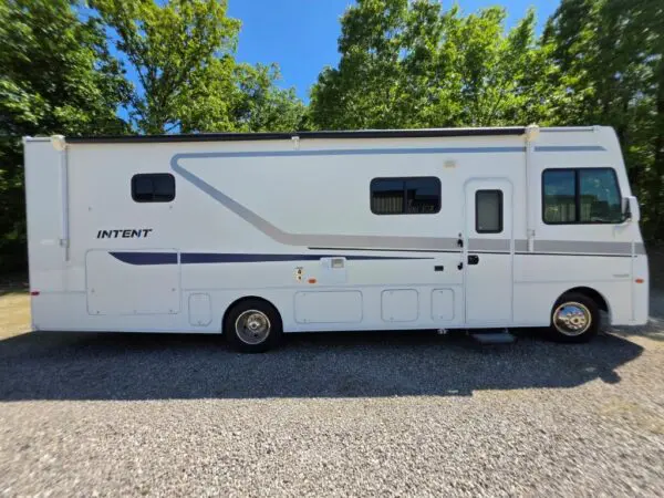 White motorhome parked on gravel driveway.
