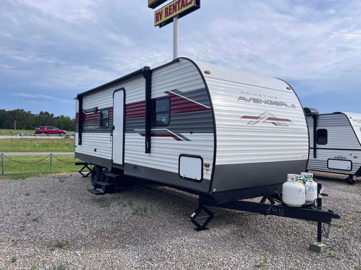 White and red travel trailer parked outdoors.